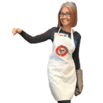 Jenny Gracia, founder of Makko’s Snack Natural Dog Bakery in San Antonio, Texas, wearing a white apron with the Makko’s Snack logo.