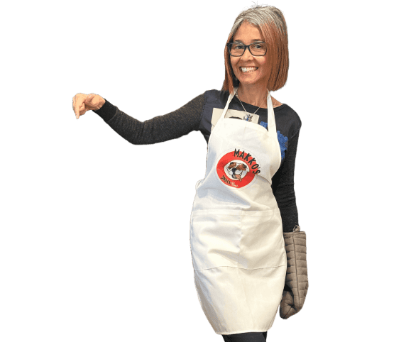 Jenny Gracia, founder of Makko’s Snack Natural Dog Bakery in San Antonio, Texas, wearing a white apron with the Makko’s Snack logo.