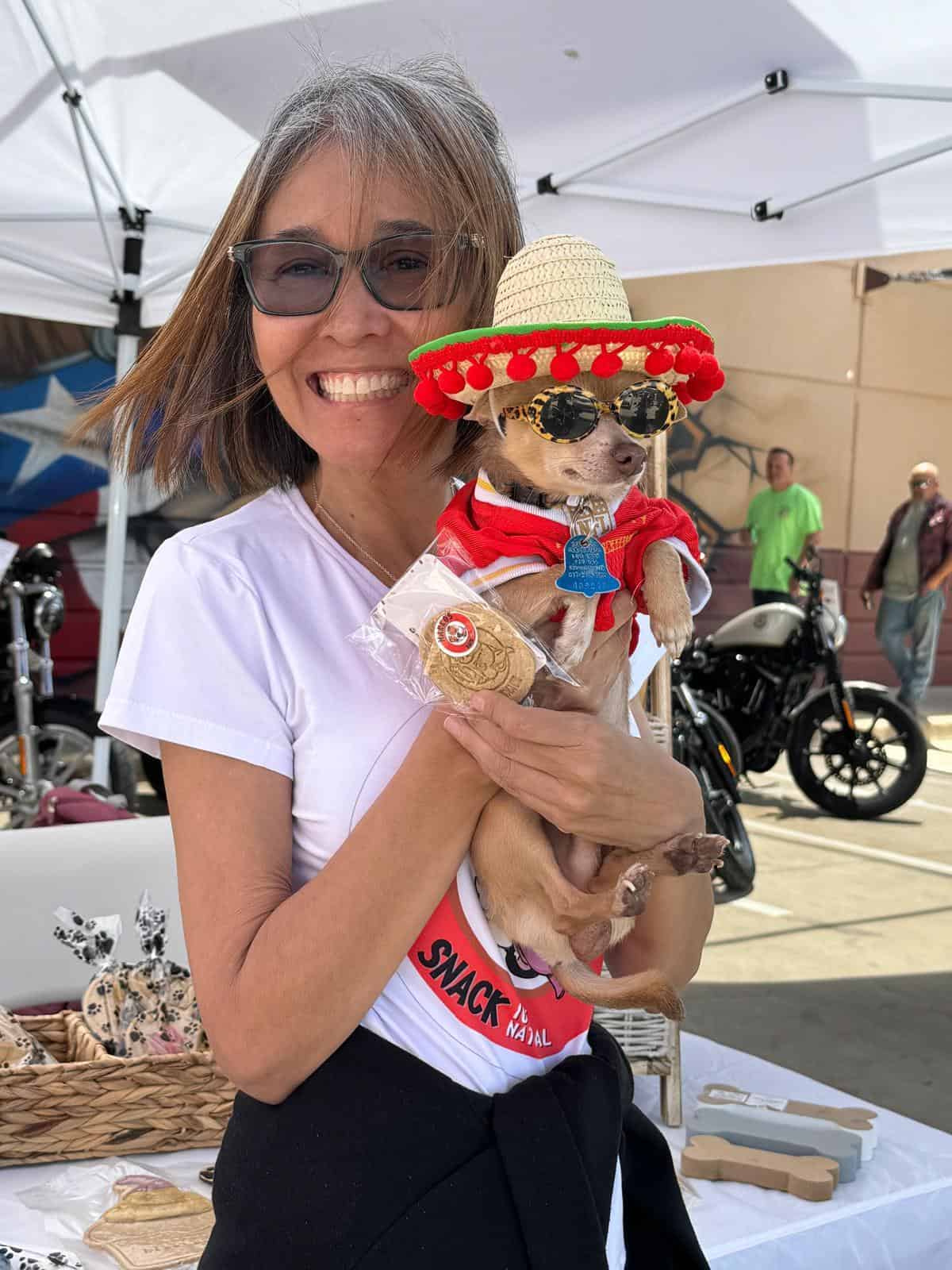 Jenny from Makko’s Snack holding a happy dog enjoying a natural birthday cake in San Antonio, Texas
